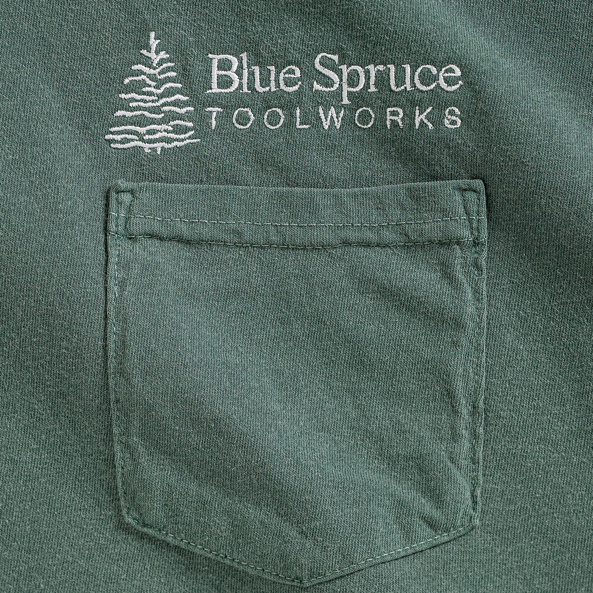 Close-up view of the front T-shirt pocket and Blue Spruce logo.