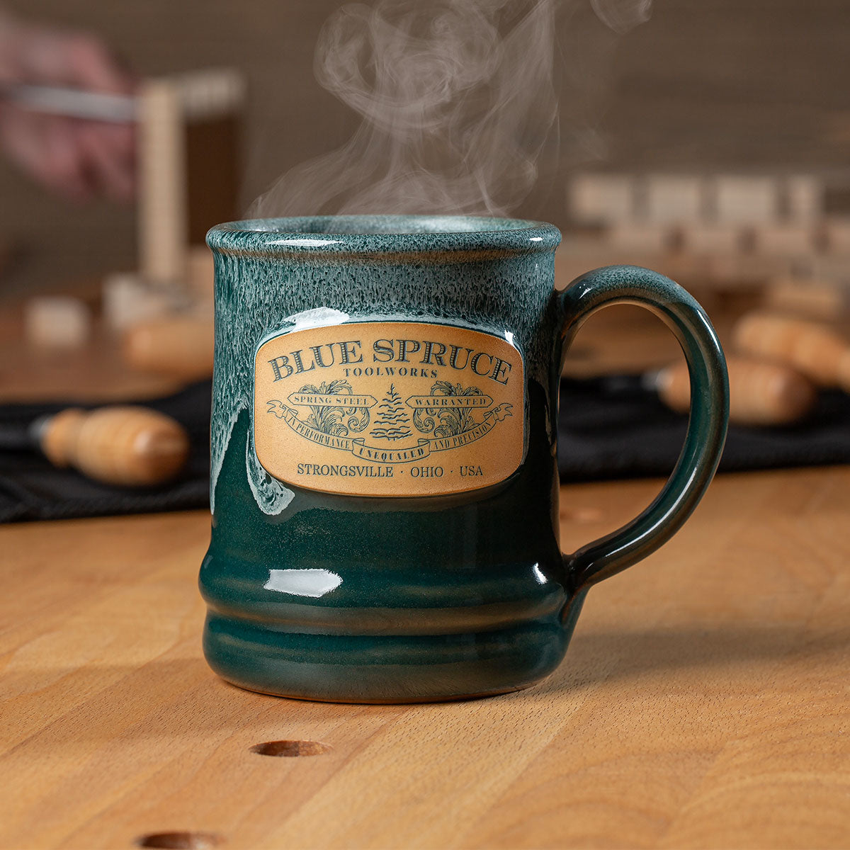 The Blue Spruce 2024 Signature Mug sitting upon a workbench. 